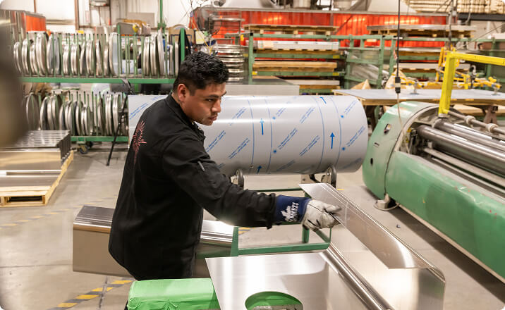Worker forming aluminum cylinder in manufacturing facility for forestry industry