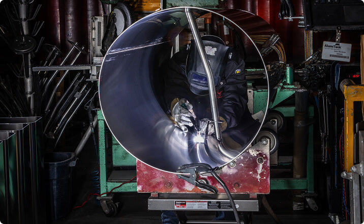 Welder working inside large aluminum pipe for government industry