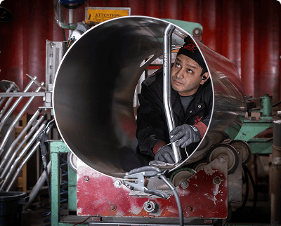 Worker operating a large circular metal rolling machine in an industrial manufacturing setting