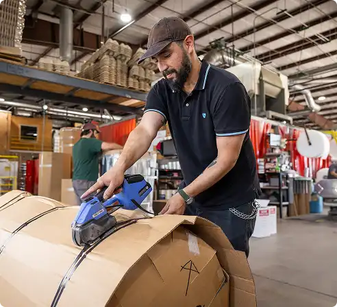 Man using a box cutter in a warehouse setting