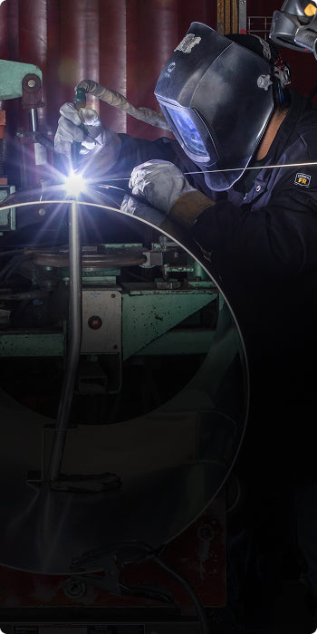 Person welding with protective gear in a workshop setting