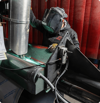 Person welding metal with protective gear in a workshop setting