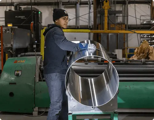 Person working with a large metallic object in an industrial setting
