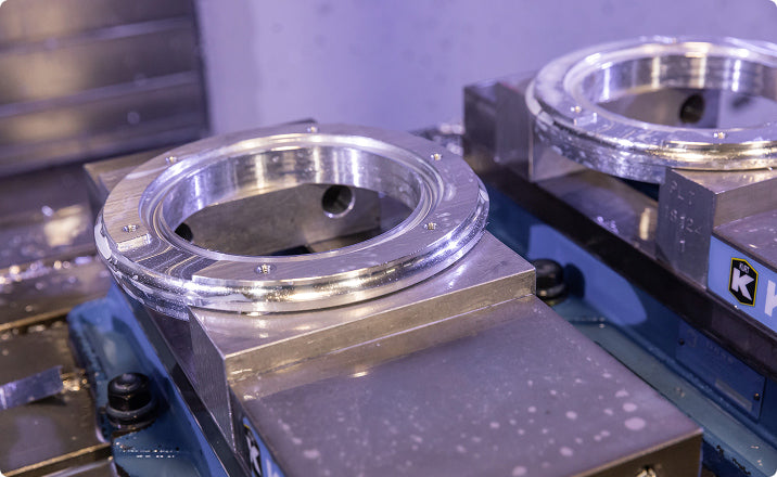 Two precision-machined aluminum ring components mounted on CNC machine fixtures in an industrial manufacturing environment