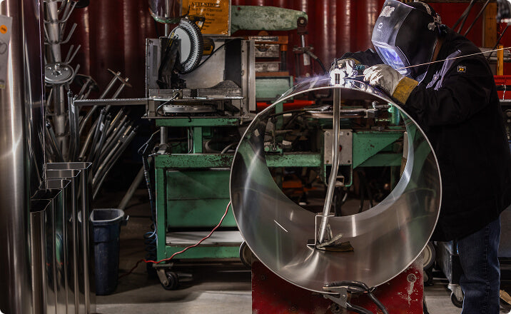 Welder fabricating large aluminum tank for emergency services