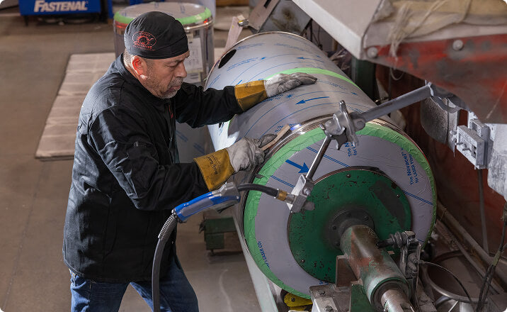Technician working on large aluminum cylindrical tank for marine industry