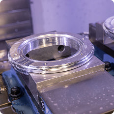 Two precision-machined aluminum ring components mounted on CNC machine fixtures in an industrial manufacturing environment