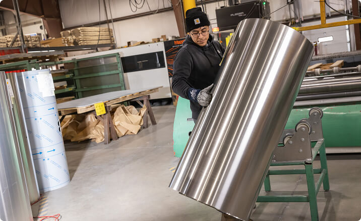 Worker rolling aluminum sheet for military industry tank production