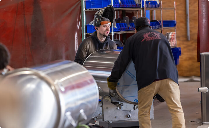 Workers handling aluminum cylindrical tanks for oil and gas industry
