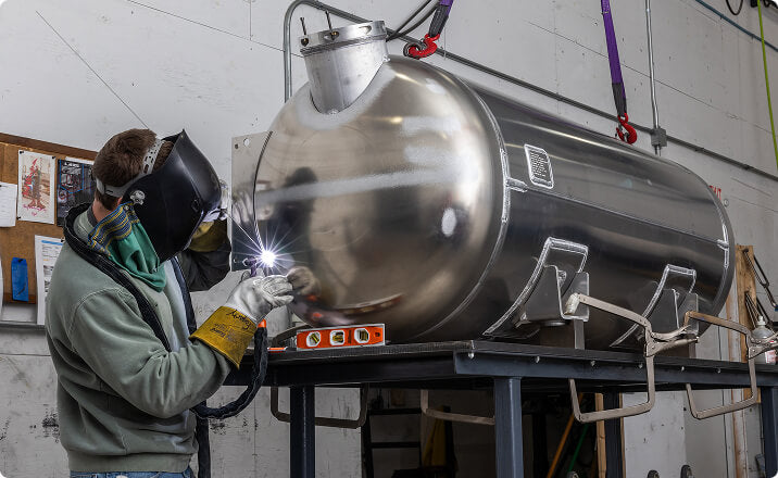 Welder working on large aluminum tank for owner operators