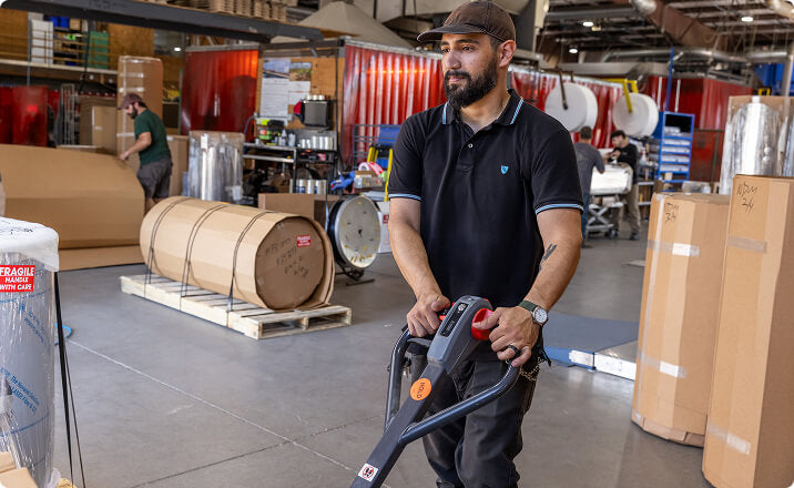 Worker operating pallet jack in recreational vehicles aluminum tank warehouse