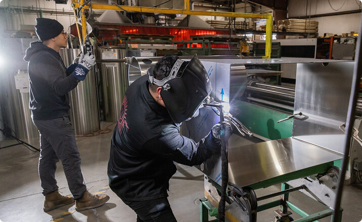 Workers welding aluminum tanks for trailer rental service industry