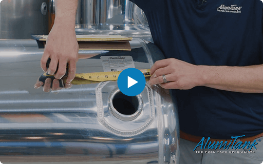 Person measuring a fuel tank with a tape measure, wearing an Alumitank shirt.