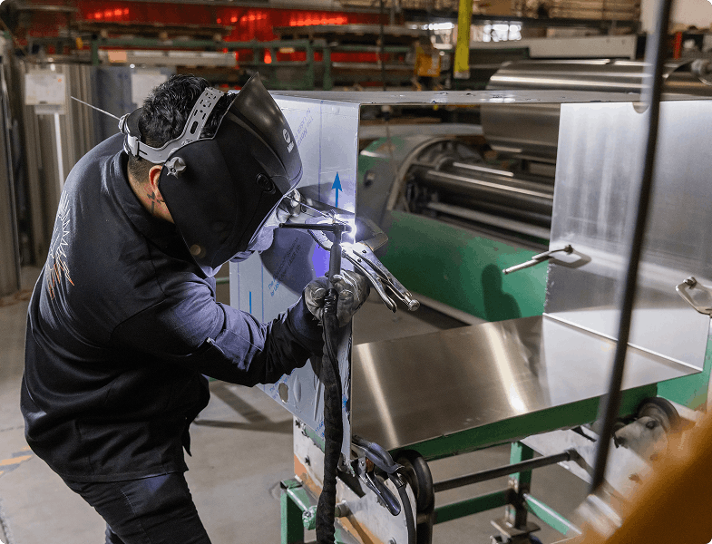 Person welding metal in a factory setting