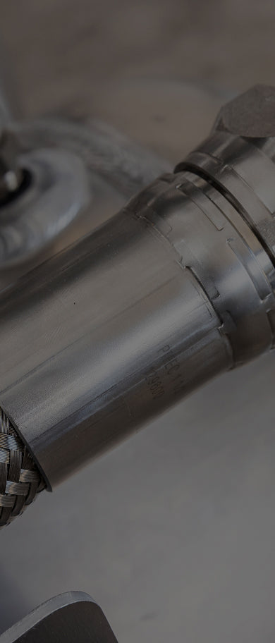 Close-up of a polished aluminum fuel tank fitting and metal hose connection